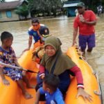 Petugas BPBD saat mengevakuasi seorang ibu