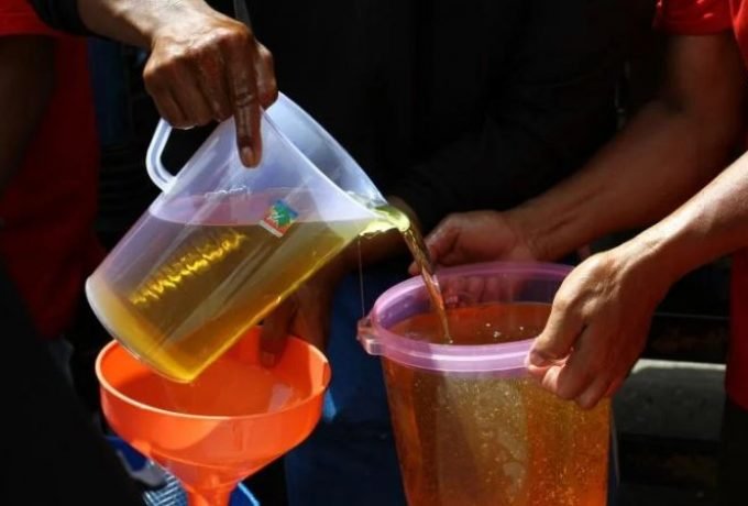 Pekerja menuangkan minyak goreng