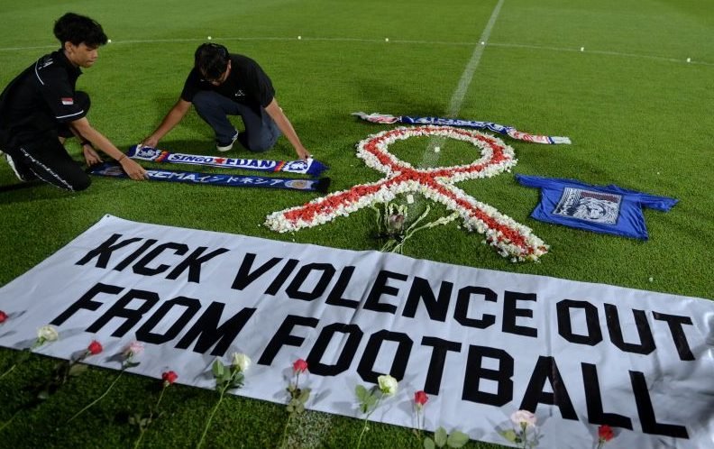 Suporter sepak bola meletakkan atribut Arema